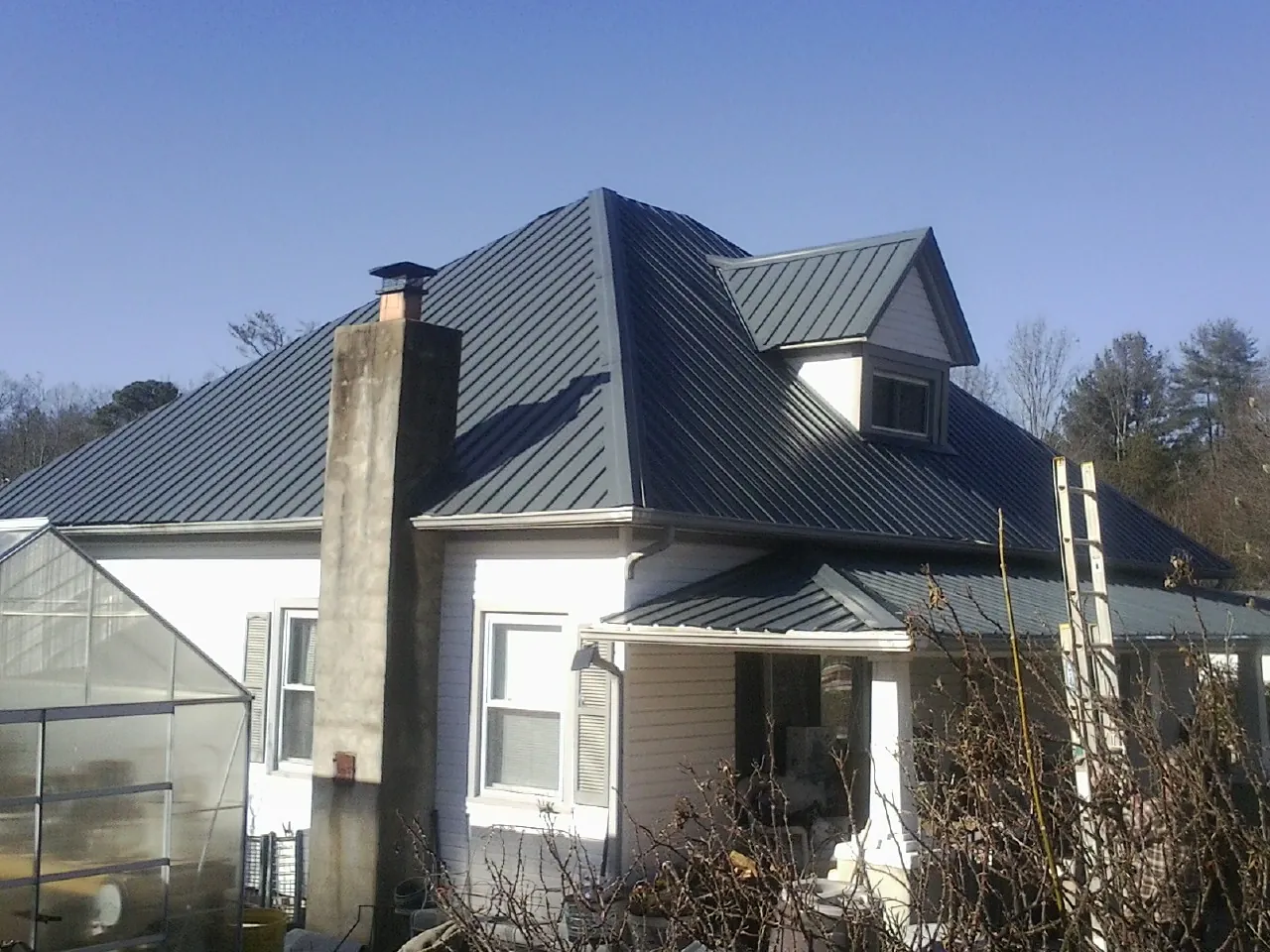 Dark blue standing seam metal roof on a white farmhouse with dormer — Slate & Tile Roof Repair by Roofing Brothers in Truro