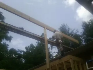 Carpenter setting a ridge beam over a new addition frame — Ice Dam Removal by Roofing Brothers in Truro