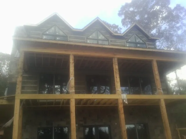 Dormers and porch framing on a large log home under construction — Roof Coating work by our crew in Truro