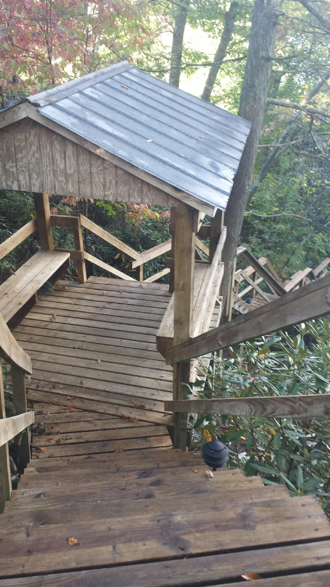 Metal roofed shelter over wooden steps on a wooded walkway — Skylight Repair & Installation work by our crew in Truro